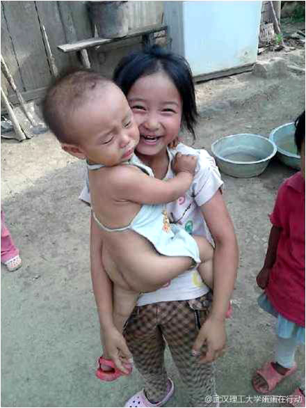 7月17日,“蛋蛋在行動”團隊田壩分隊對支教的孩子們進行了家訪,并給孩子們帶去了簡單的衣物。一名隊員說:“現在終于了解孩子們為什么會遲到,還有為什么常有‘小黑手’和小傷口,這里的山路真的很難走,有的孩子上學前還得先給牛割草……”圖上的小女孩雖然年齡不大,但照顧弟弟已經十分嫻熟。